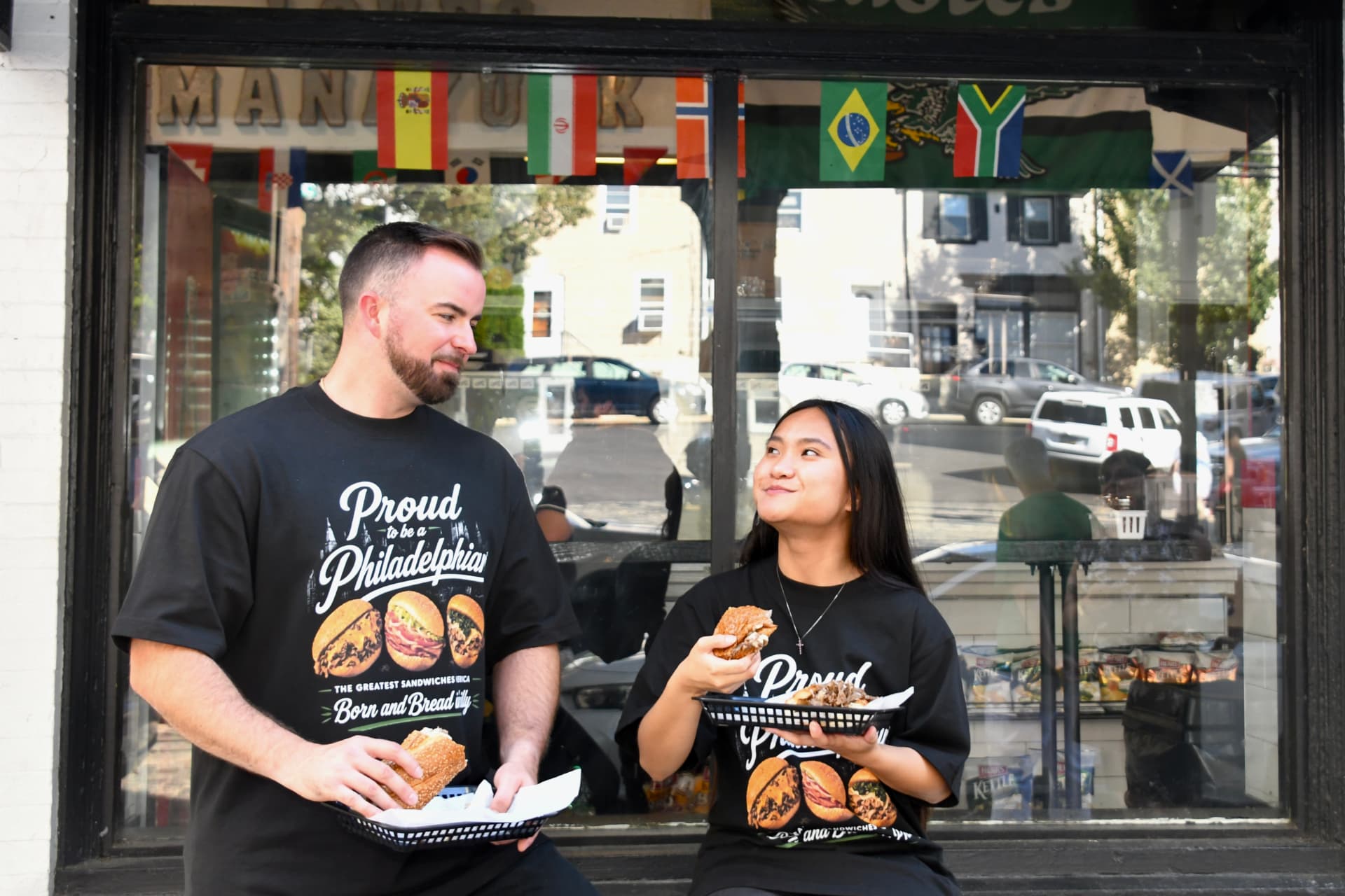 Models eating sandwiches in Born and Bread tees outside a Philadelphia sandwich shop